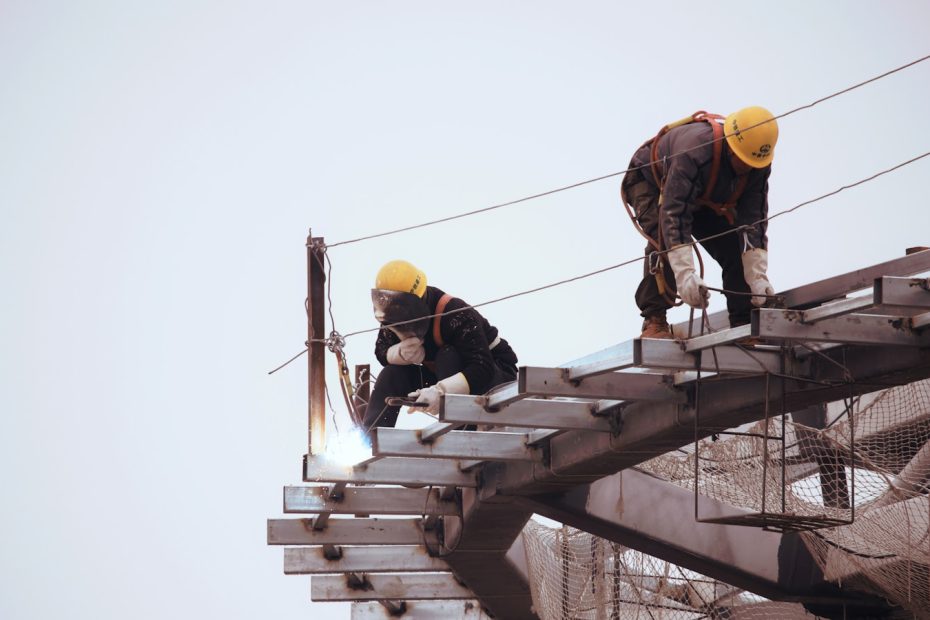 man in black jacket and yellow hard hat standing on top of building during daytime